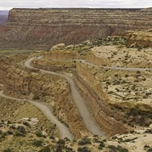 USA, Utah, cars on dirt road climbing plateau in desert, autumn