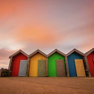 Vivid coloured beach huts at sunset