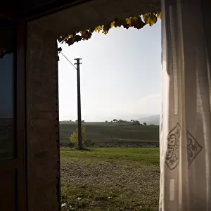 A window looking out to morning hill landscape of Val d Orcia