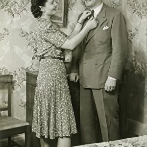 Woman adjusting mans tie at dressing table