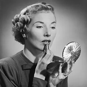 A woman applying her lipstick with the aid of a powder compact, circa 1955. (Photo by H. Armstrong Roberts/Retrofile/Getty Images)