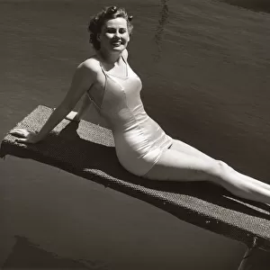 Woman in bathing suit sitting on diving board