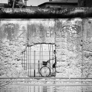 Frau radelt an einem Teil der Berliner Mauer vorbei.