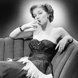Woman in evening dress smoking cigarette (B&W), portrait