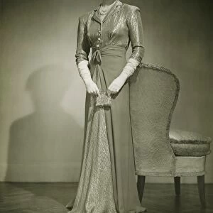 Woman in evening dress standing indoors, (B&W)