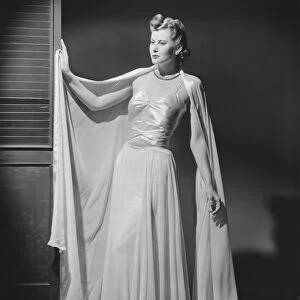 Woman in evening gown posing in studio (B&W), portrait