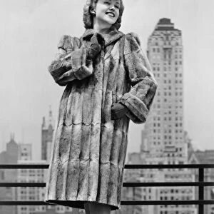 Woman in fur coat and fancy hat standing on outside terrace (B&W)