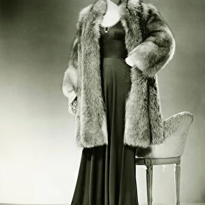 Woman in fur coat posing in studio, (B&W), portrait