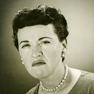 Woman grimacing in studio, (B&W), close-up, portrait