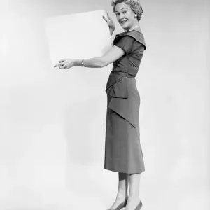 Woman holding blank piece of paper, portrait, studio shot Woman holding blank piece of paper, portrait, studio shot