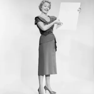 Woman holding blank piece of paper, portrait, studio shot Woman holding blank piece of paper, portrait, studio shot