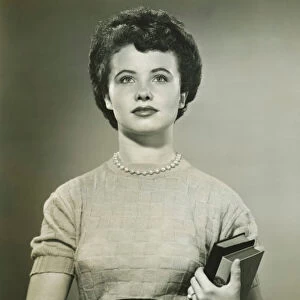 Woman holding books, posing in studio, (Portrait), (B&W)