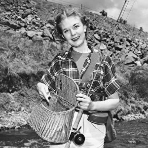 Woman holding creel and fishing rod