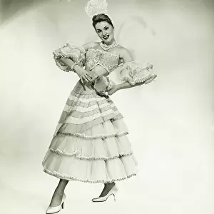 Woman in Latino dance costume posing in studio, holding drum, (B&W)