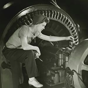Woman operating machine in factory, (B&W)