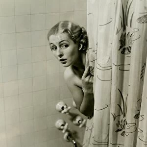 Woman peeking from behind shower curtain