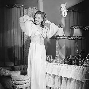 Woman posing by vanity table in opulent bedroom, (B&W), portrait