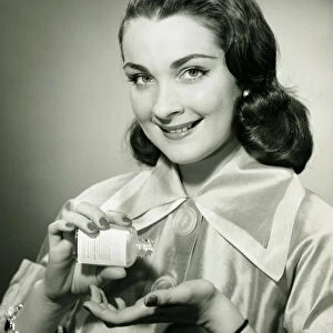 Woman pouring pills from bottle into hand in studio, (B&W), portrait
