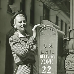 Woman putting letter into mailbox, (B&W)