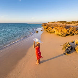 Woman with red dress on Osprey Bay beach at sunset. Western Australia