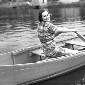 Woman rowing boat on lake, (B&W), portrait