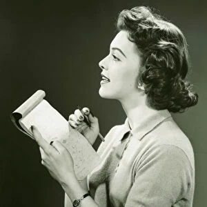 Woman secretary making notes in notebook, (B&W)