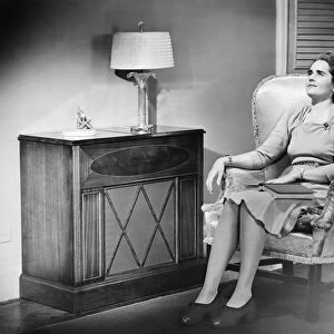 Woman sitting in armchair with book on knees (B&W)