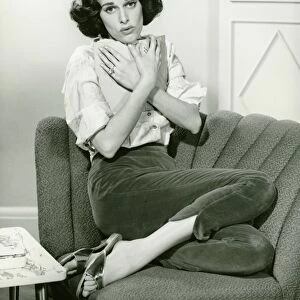 Woman sitting on couch, cuddling book, (B&W), portrait