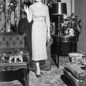 Woman standing in rich living room, holding cigarette, (B&W)
