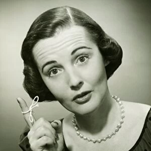 Woman with string tied around finger in studio, (B&W), (Close-up), (Portrait)