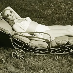 Woman sun tanning on meadow, (B&W), elevated view