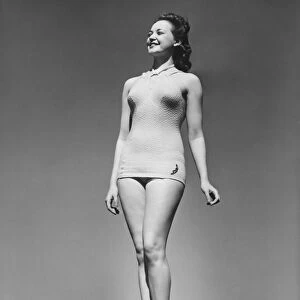 Woman in swimsuit posing in studio (B&W), low angle view