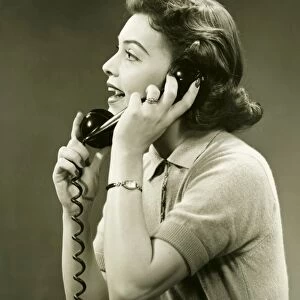 Woman talking on landline phone in studio, (B&W)