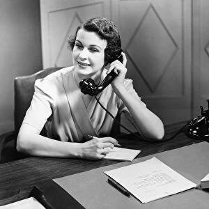 Woman talking on phone at desk (B&W)