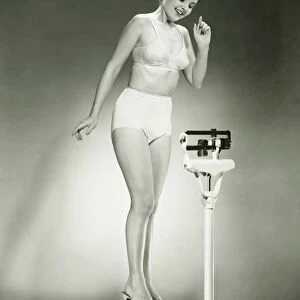 Woman in underwear standing on scale, (B&W)