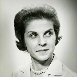 Woman wearing pearls looking away, posing in studio, (B&W), portrait