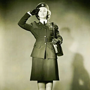Woman wearing World War II uniform saluting in studio, (B&W), portrait