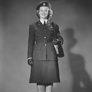 Woman in World War II military uniform posing in studio (B&W), portrait
