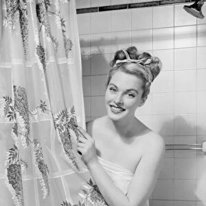 Woman wrapped in towel peeping through shower curtain (B&W), portrait