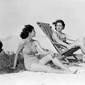 Two women in bathing suits on windy beach