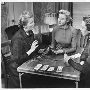 Three women playing cards at home, (B&W)