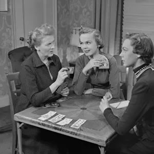 Three women playing cards in living room