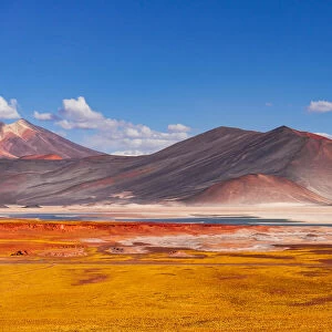 Yellow volcanic scenery with colorful mountains and a blue salt lake