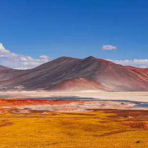 Yellow volcanic scenery with colorful mountains and a blue salt lake Yellow volcanic scenery with colorful mountains and a blue salt lake