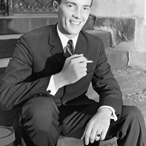 Young businessman sitting on steps, smoking cigarette, (B&W)