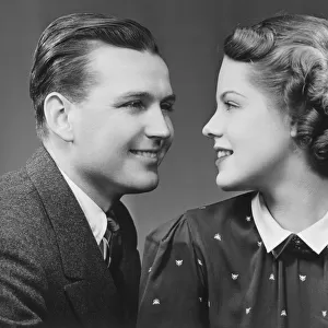 Young couple looking in eyes in studio, (B&W), portrait