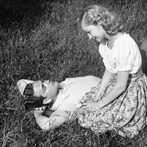 Young couple resting on lawn, (B&W)