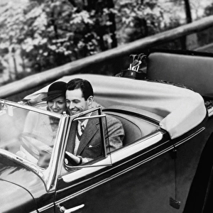 Young Couple in Vintage Soft Top Car with Golf Clubs on Back Seat