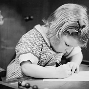 Young girl (4-5) working on school table, (B&W), close-up