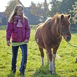 Young girls walking with a pony